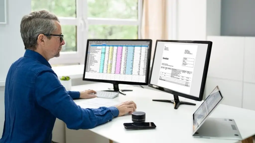 Profesional trabajando en oficina con dos pantallas durante la digitalización de facturas con software contable de Stratic